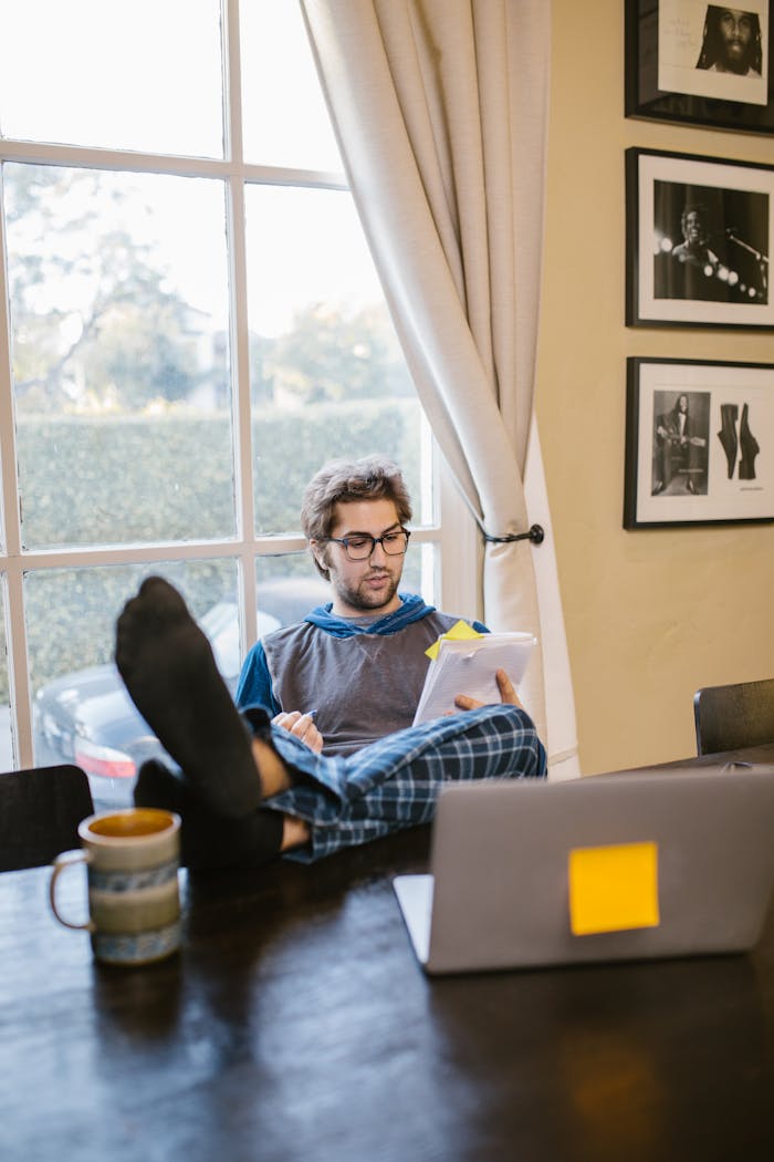Man studying comfortably at home with a laptop and coffee, featuring a relaxed and cozy setting.